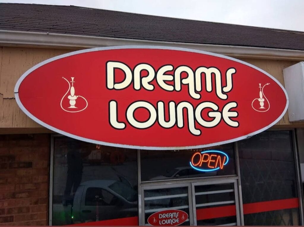Sign for "Dreams Lounge" featuring a hookah icon, with an illuminated "OPEN" sign, indicating a welcoming atmosphere for patrons