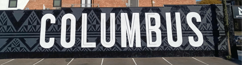 Large mural featuring the word "COLUMBUS" in bold, stylized letters, set against a geometric black and white pattern, highlighting urban art.